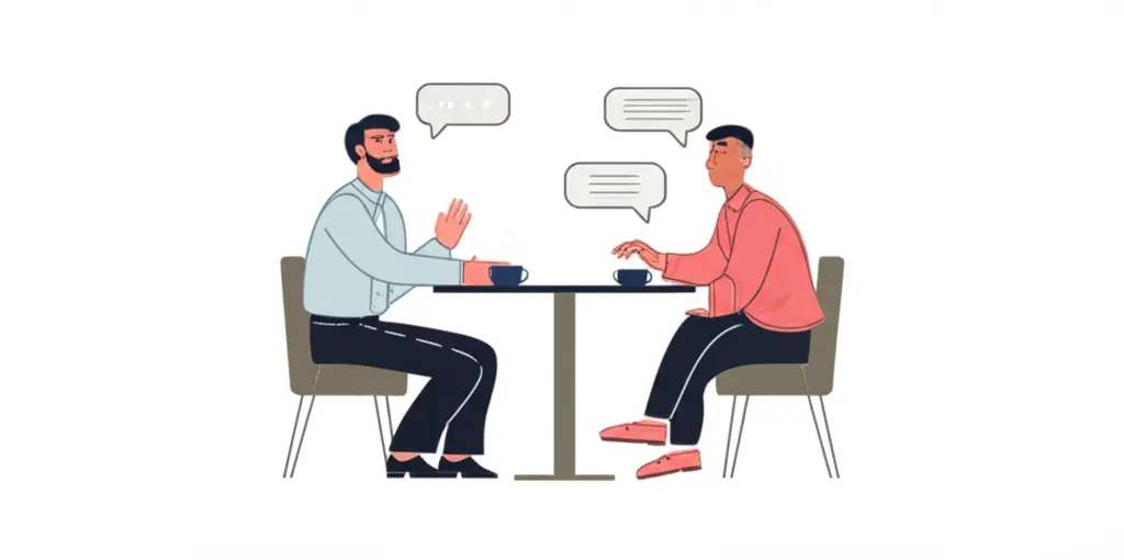 Mentor and mentee discussing real estate strategies over coffee