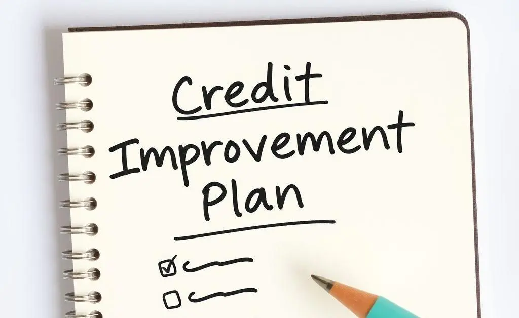 A notepad with a hand writing 'Credit Improvement Plan' and a checklist