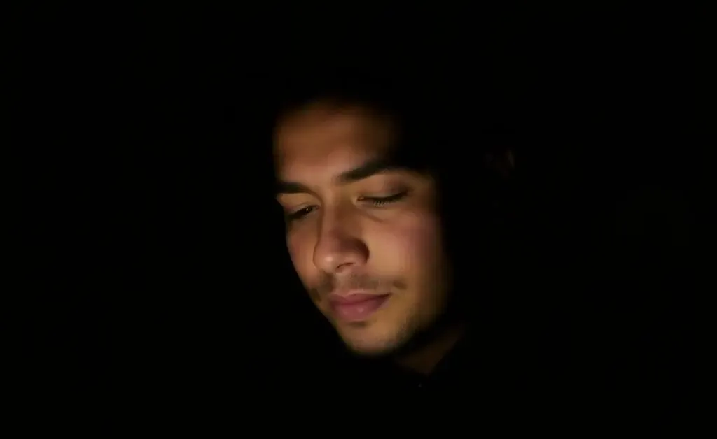 A person looking at a phone in dark mode, appearing relaxed and comfortable
