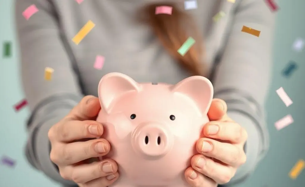 Person celebrating savings milestones with a piggy bank