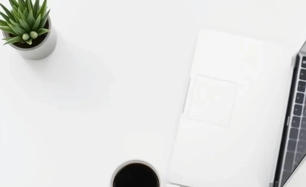 A clean, minimalist desk setup with a laptop, a plant, and a cup of coffee.