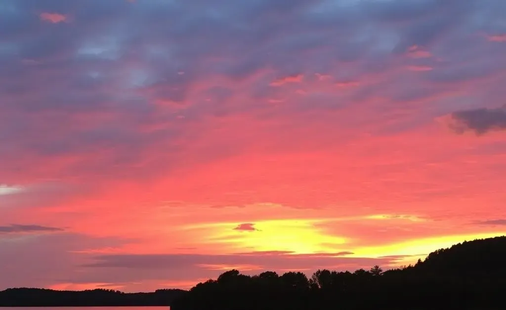 A peaceful sunset over a calm lake with vibrant colors reflecting in the water.