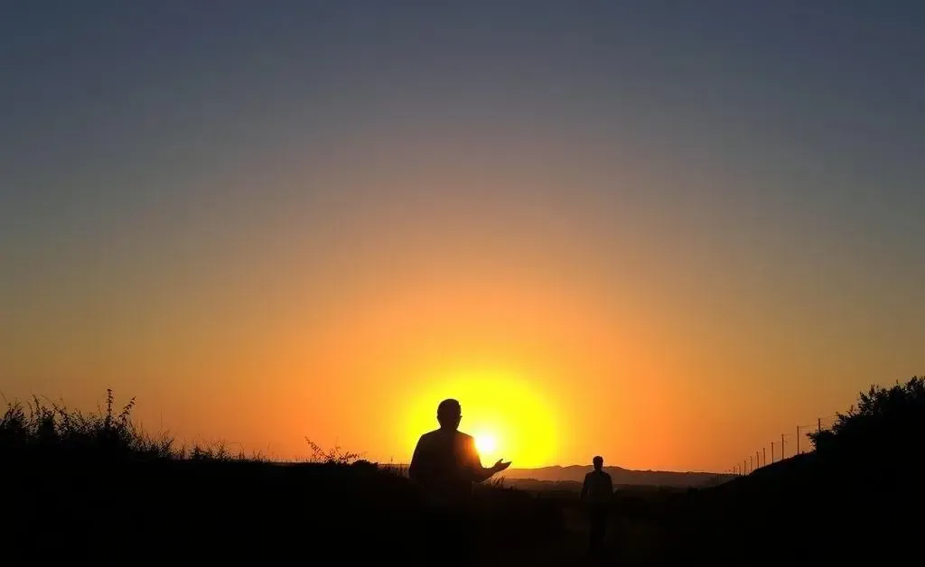 A silhouette of a person walking on a path during sunset, casting long shadows.