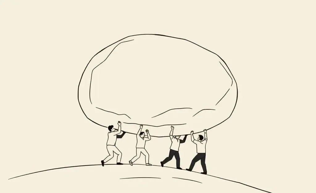 Team working together to push a boulder uphill